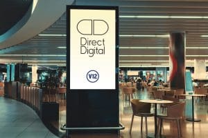 Digital LCD advertising display featuring Direct Digital and V12 logos, in a shopping mall food court