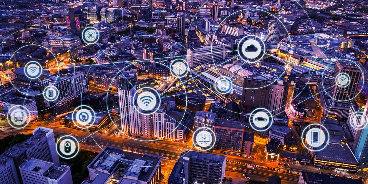 V12 Telecom's Multi-Network Data SIMs maintaining constant connectivity for multiple interlinked devices and infrastructure installations overlying backdrop of UK cityscape at dusk.
