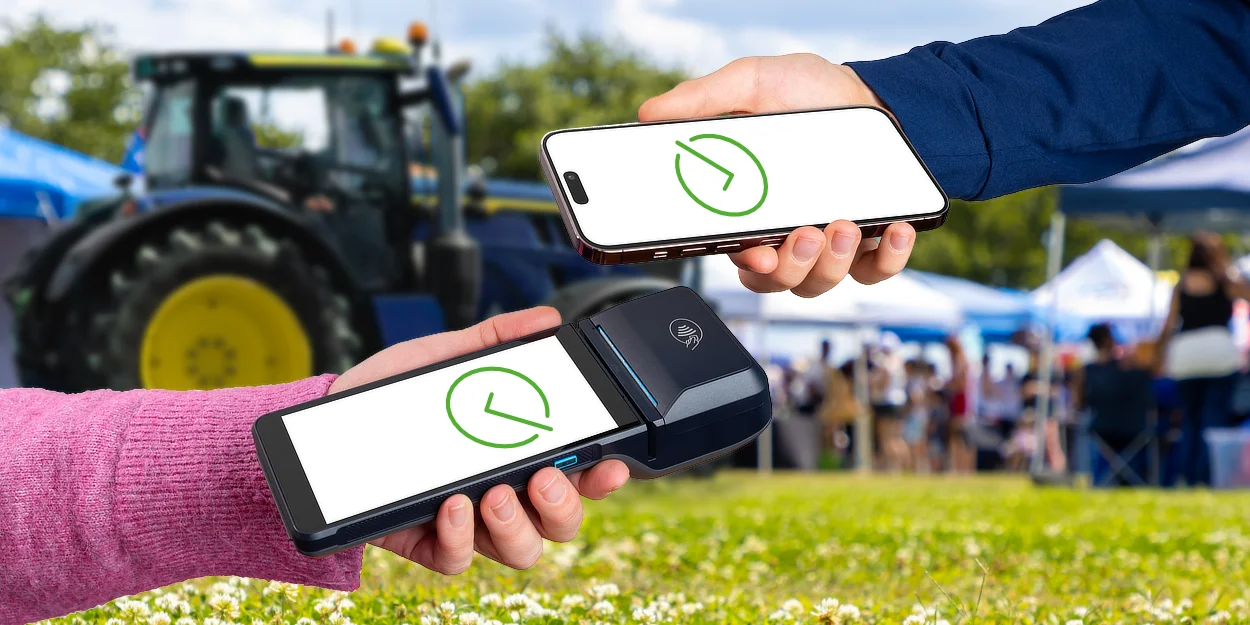 Against the backdrop of a traditional British village show, a customer makes a successful payment by hovering a smartphone above a portable wireless POS terminal.